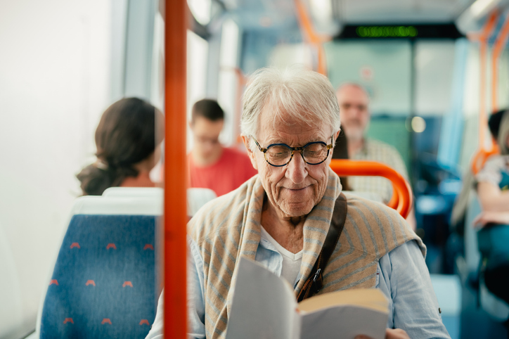 A senior man reading a book while traveling by bus. when should seniors stop driving